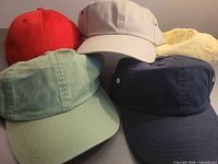 Top view of five blank baseball caps in assorted solid colours
