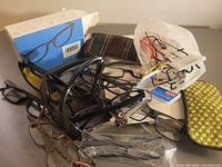 pile of assorted reading glasses, cases, boxed pair