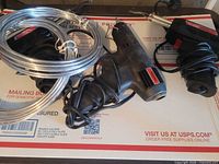 Three corded hand tools and coil of wire on USPS box