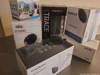 Group shot of five boxed security cameras including Sunrise, Trace Premise, generic IP Camera and two bullet camera boxes