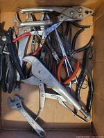 Assortment of pliers and adjustable wrench inside cardboard box