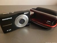 Front of Olympus X-42 camera beside open carrying case