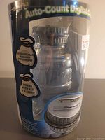 Front of packaged digital coin bank showing clear jar and LCD lid
