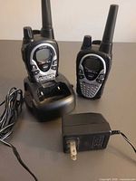 Two Midland LXT780 walkie talkies in charging cradle with AC adapter
