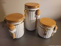 Front view showing all three ceramic canisters with lids and spoons