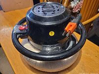 Top view of black steering-wheel handled electric car buffer with power cord and red power button