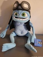 Full view of plush sitting upright on surface with tag attached