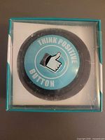 Front view of boxed Think Positive Button