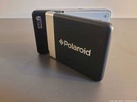 Front view of folded Polaroid device showing logo and ZINK badge