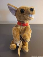 Front view of brown plush dog with red collar and leash