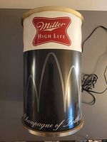 Side view of cylindrical Miller High Life advertising lamp showing graphics and power cord