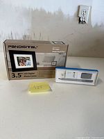 Front view of boxed Pandigital photo frame and boxed Microsoft Surface Pen
