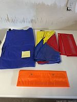 Folded blue chart, folded multicolour chart, red and orange pocket strips on table