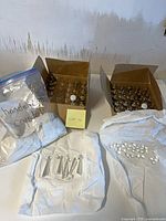 Two boxes of white drawer knobs, bag and loose chandelier crystals on table