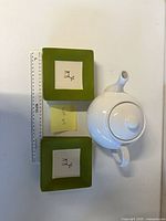 stacked square reindeer plates beside teapot with ruler for scale