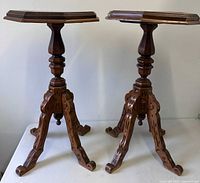 pair of carved wooden pedestal tables full view