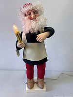 Front view of Elco Motionette mechanical elf holding lit candle on base