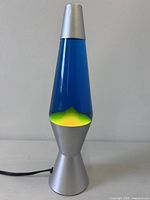 Full view of lava lamp upright showing silver cap, blue liquid and yellow-green wax, base visible