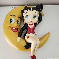 Front view showing Betty Boop on yellow crescent moon, hanger loops visible