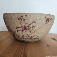 Side view of speckled stoneware bowl showing red floral design