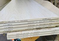 stack of light wood-tone ceramic tiles showing printed edge markings