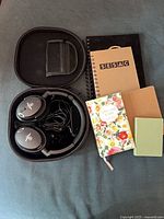 Headphones in case, five notebooks arranged beside