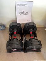 Pair of adjustable dumbbells in trays with owner’s manual