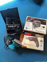 Overview of boxed Craftsman saw, boxed Skil drill, inflator case, teal sander