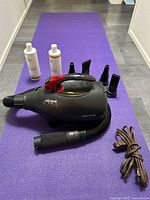 Full lot showing dryer, hose, four nozzles, power cord, shampoo and conditioner on purple mat