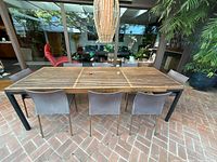 Full view of teak slatted table and eight sling chairs