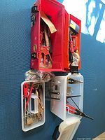 Overall view of red toolbox, white organizer and translucent tote with assorted hand tools and hardware