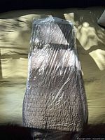 Sealed silk comforter folded in plastic wrap on bed