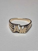 Front view of yellow gold ring showing raised "AM" initials and stepped sides