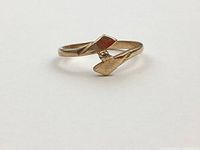 Front view of yellow gold bypass ring showing heart-shaped ends and imitation diamond