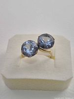 Top view of bypass ring showing two round blue topaz stones in claw settings