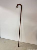Full view of wooden walking cane standing upright