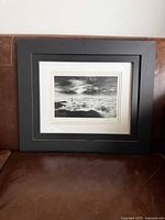 Full framed photo on leather couch showing black frame, white mat, and print