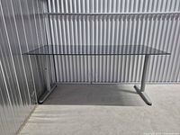 Full view of glass top desk against corrugated wall