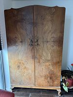 Front view of closed wardrobe showing burl veneer and brass pulls