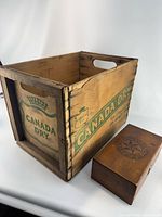 Crate front showing Canada Dry shield logo and small wooden box beside