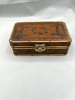 Front angled view of closed pigskin-covered box showing brass clasp and edge bands