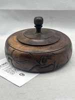 Side view of carved wooden box with lid showing rhinoceros relief