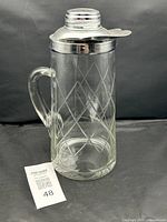 Full view of glass pitcher with chrome lid and handle