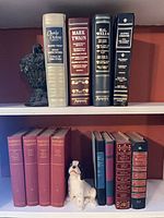 Shelf with four faux-leather literature volumes and cast metal bookend