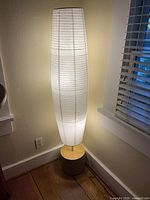 Full view of illuminated column floor lamp in corner