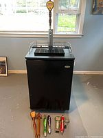 Front view of kegerator with tower and tap handles arranged on floor