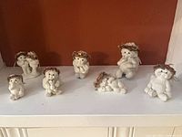 Front view of seven cherub figurines lined on shelf