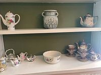 Overview of shelves showing all tea service items and decorative vase