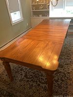 Full view of oak dining table fully extended with leaves in place
