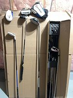 Overall view of clubs in cardboard box with headcovers visible